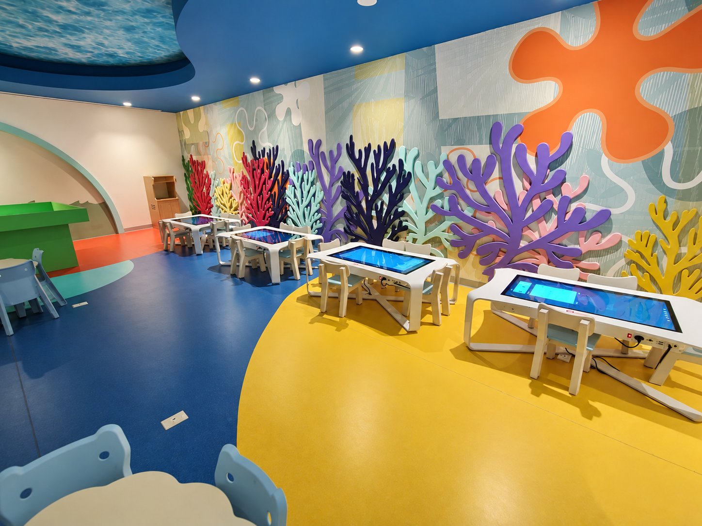 Área infantil interior equipada con mesas interactivas