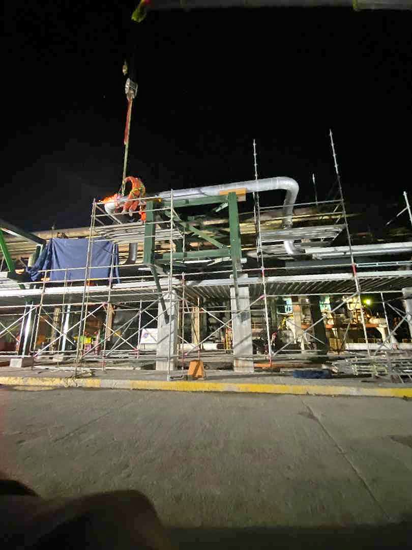 Trabajos nocturnos de montaje de tubería sobre andamios en planta